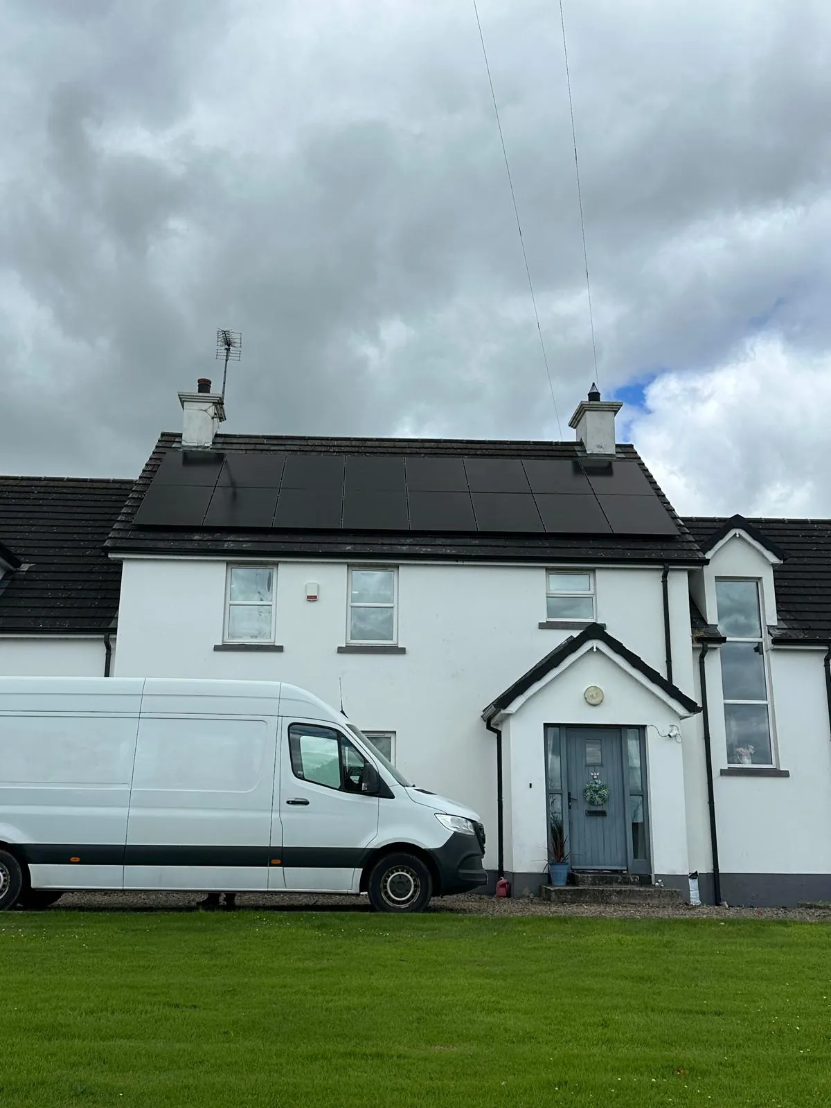 Two rows of black solar panels on a white two-storey home