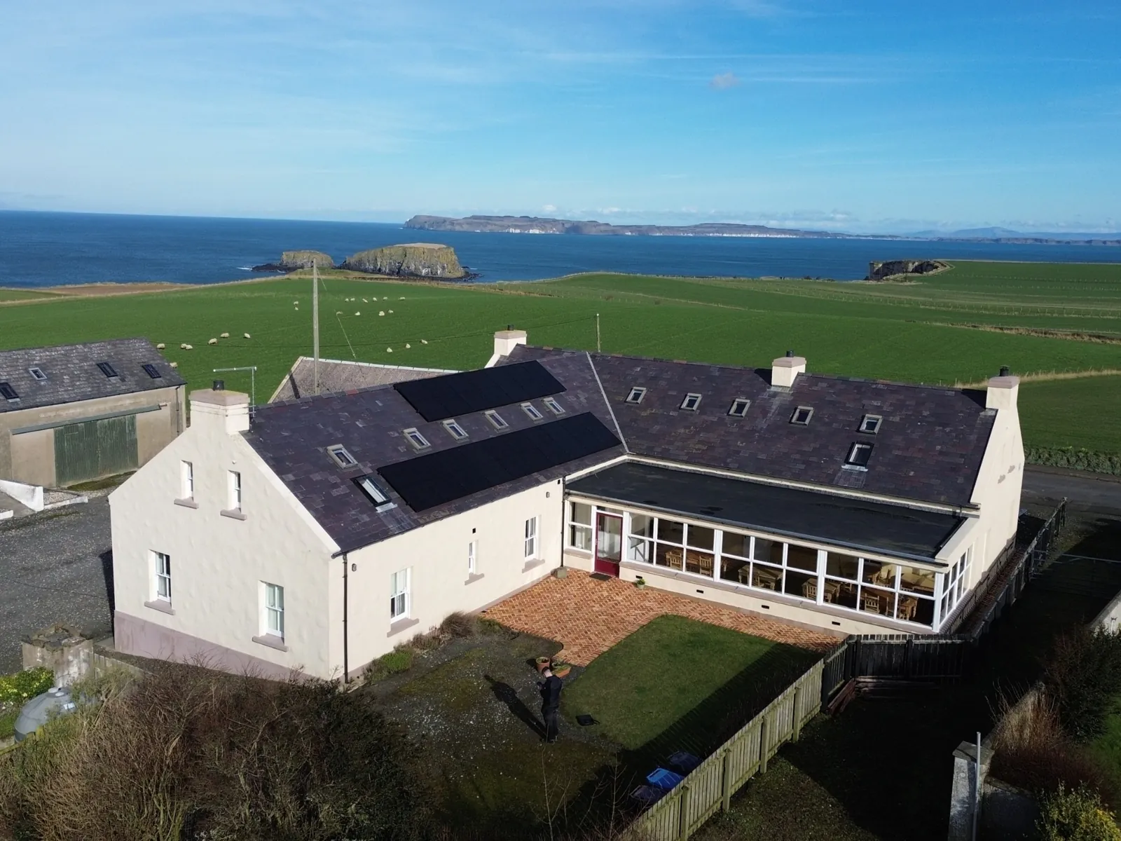 Aerial view of black solar panels on a slate roof of a coastal property, Northern Ireland