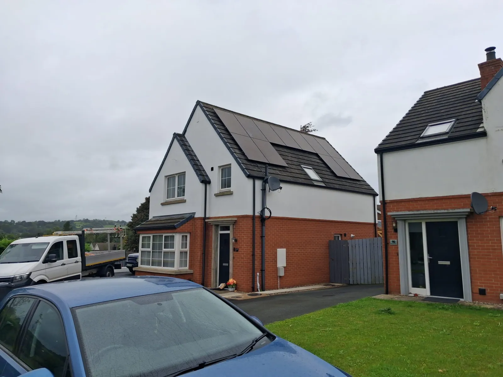 Black solar panels on the roof of a detached house around a roof window