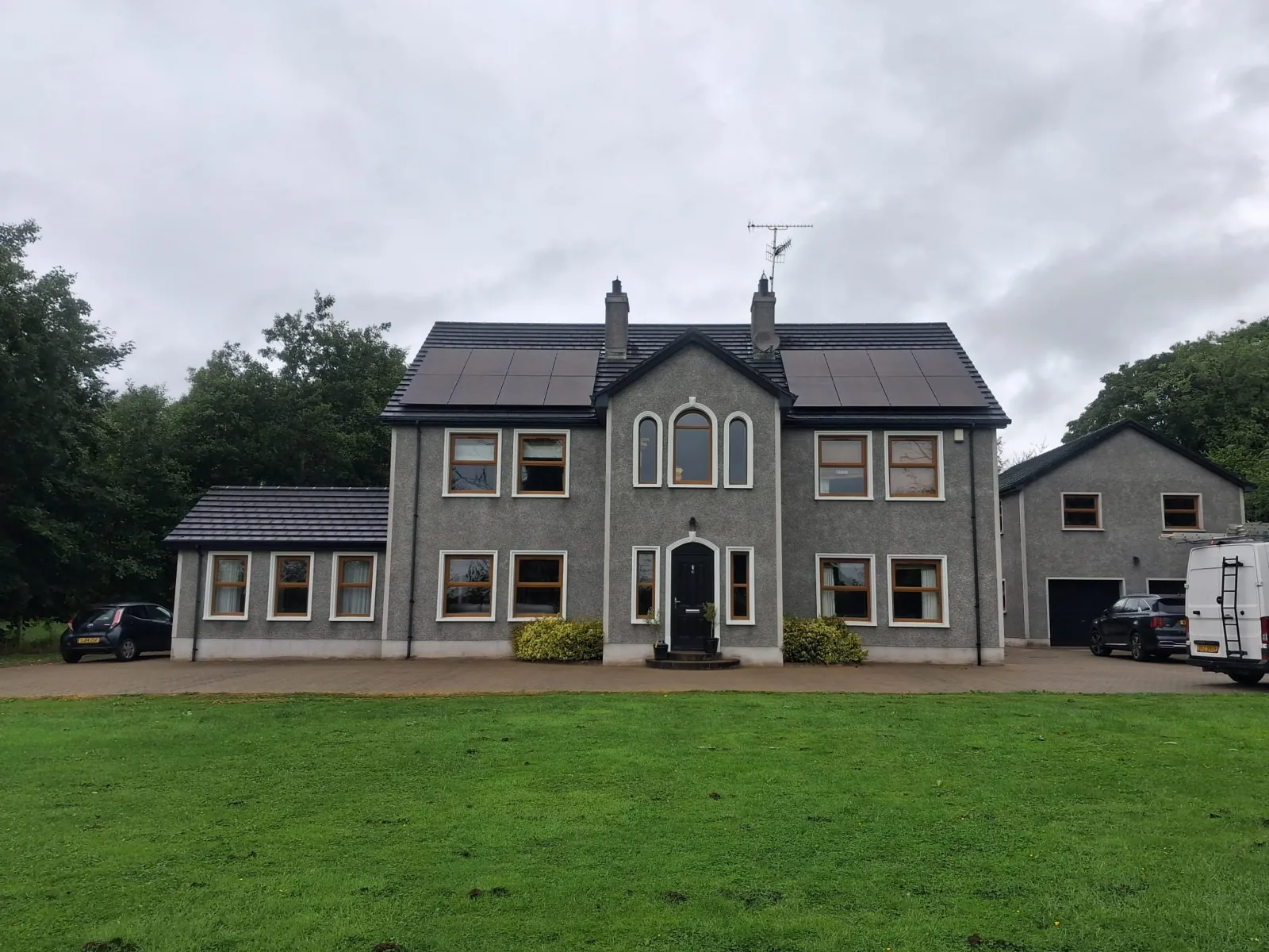 Two black solar panel arrays either side of the central gable on a large detached house