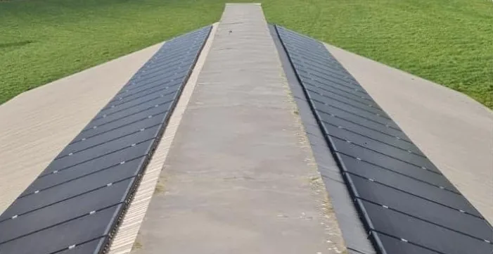 Agricultural solar panels in two rows along both sides of a long shed roof