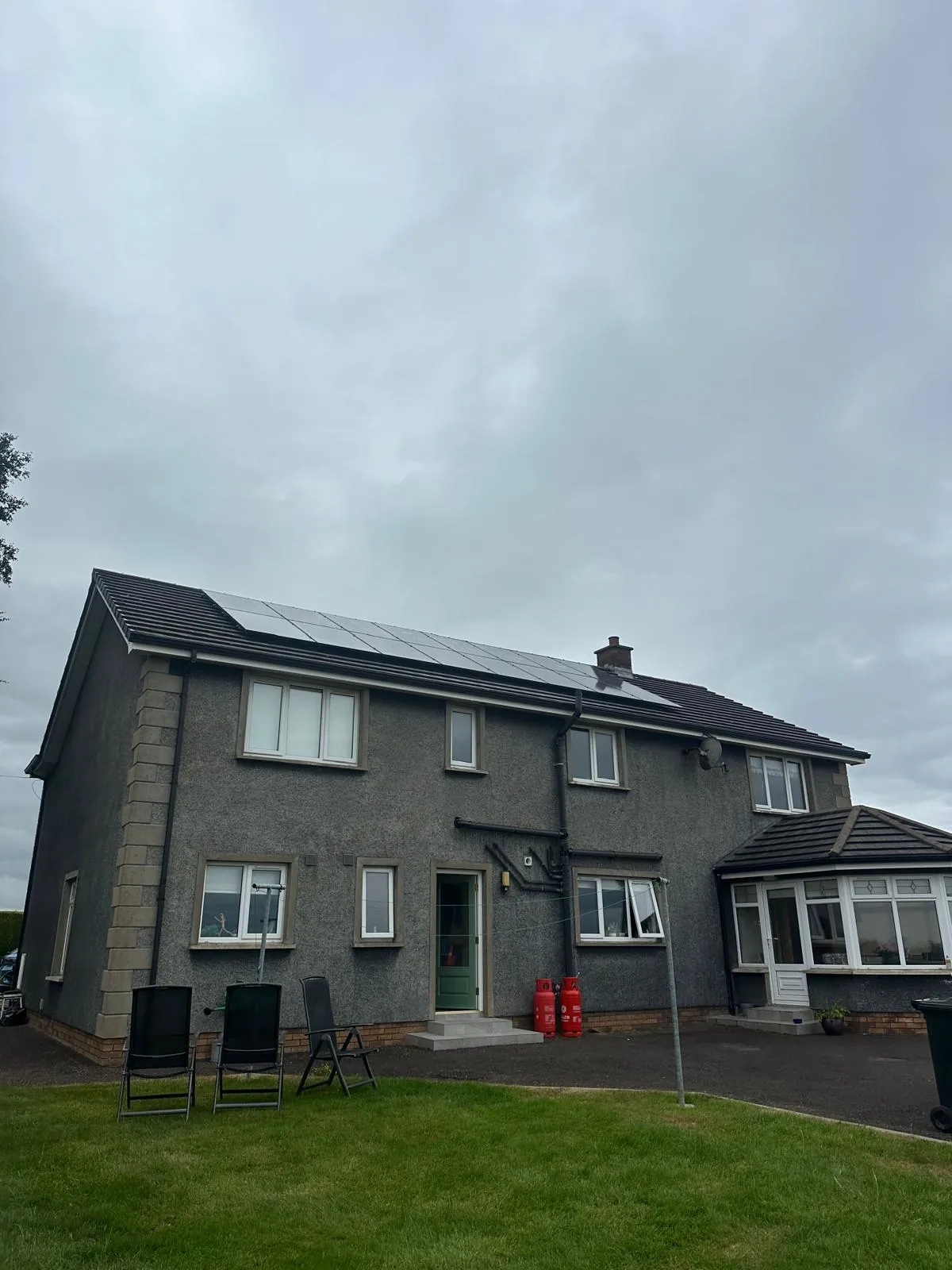 Black solar panels along the roof of a rural detached house